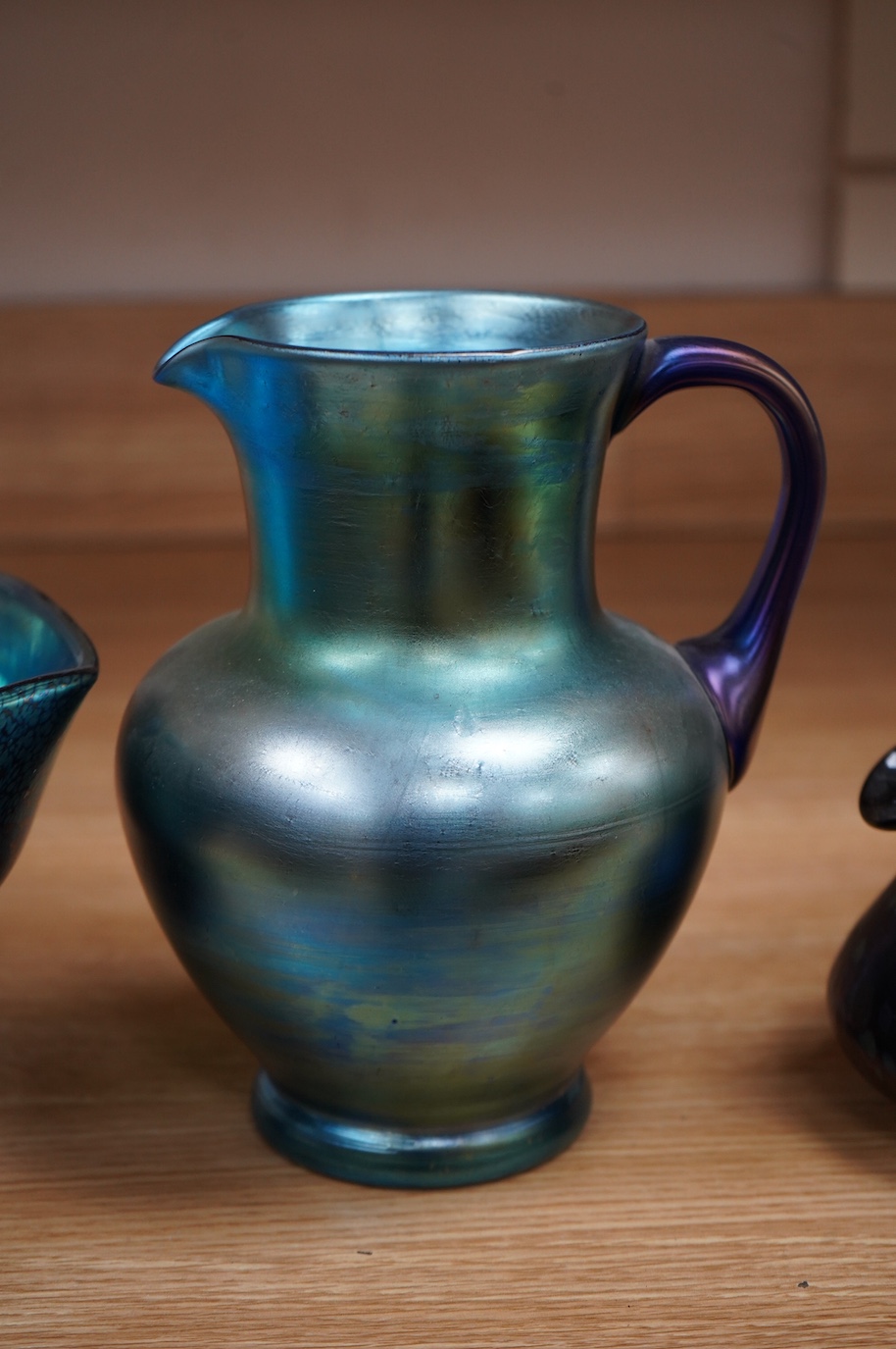 A Loetz cobalt Papillon iridescent glass footed hexagonal bowl, a Kralik blue iridescent vase and a large Bohemian iridescent glass jug (3) tallest 21cm. Condition - good